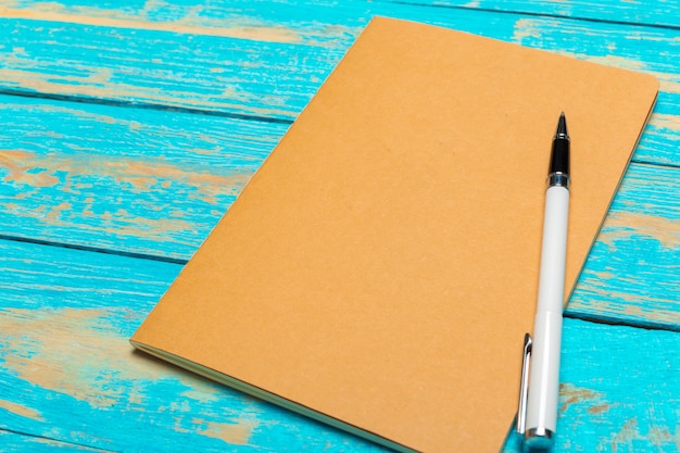 Espaço de trabalho vista superior com caderno em branco e caneta no fundo da mesa de madeira