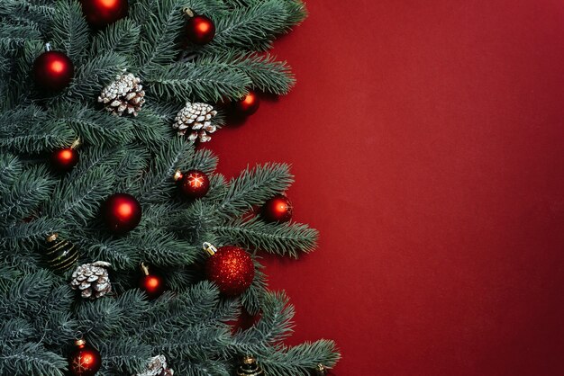 Espaço para texto entre galhos de árvores de Natal com enfeites de Natal e bolas em um fundo vermelho. Composição de Natal.