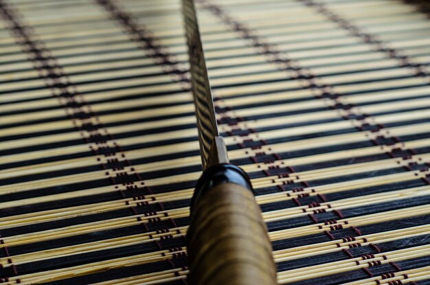 Foto espada japonesa katana na esteira de bambu foco seletivo