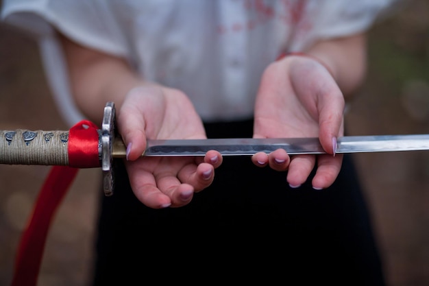 Espada samurái japonesa katana con cinta roja. Una mujer sosteniendo una espada samurái.