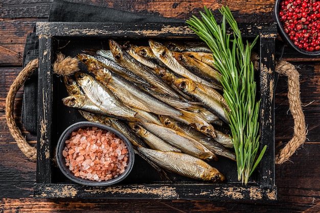 Espadín ahumado fragante y pescados de la sardina con hierbas. Fondo de madera. Vista superior.