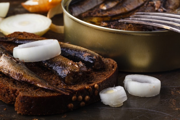 Espadines enlatados en lata con pan de centeno. En superficie rústica