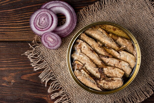 Espadines en una lata y pan sobre mesa de madera