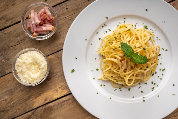 Espaguete a la carbonara em prato branco e mesa rústica