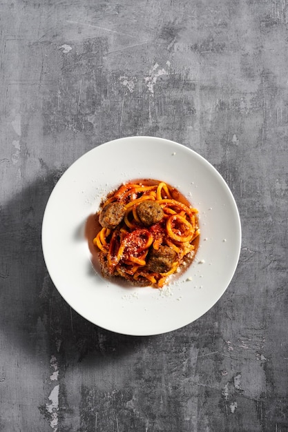 Foto espaguete caseiro com parmesão de molho de tomate e almôndegas em um fundo escuro