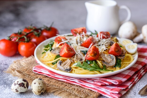 Espaguete com cogumelos, queijo, espinafre, rukkola e tomate cereja. prato italiano, cultura mediterrânea