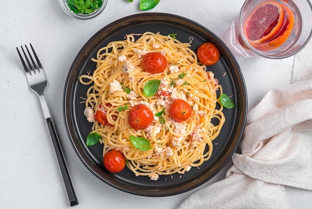 Espaguete com ervas de tomate cereja feta assado e manjericão em um fundo cinza Vista superior horizontal