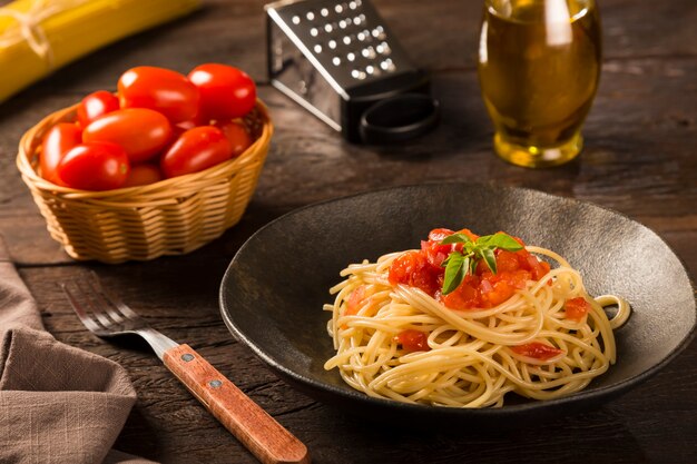 Espaguete com molho de tomate e manjericão no fundo de madeira rústico