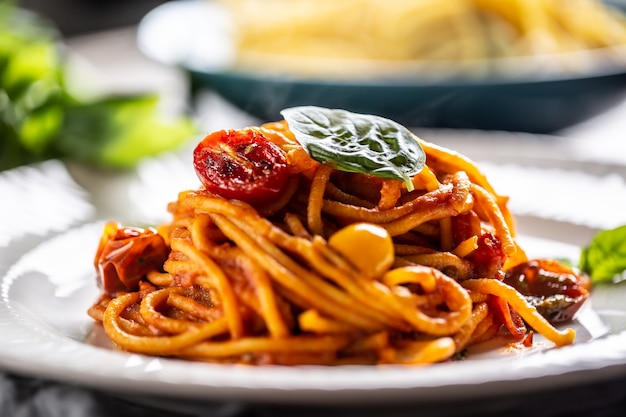 Espaguete com molho vermelho, tomate e manjericão servido em um prato.
