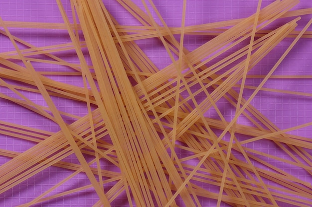 Espaguete cru em um fundo roxo Conceito de comida vegetariana Closeup de uma massa italiana Vista de cima