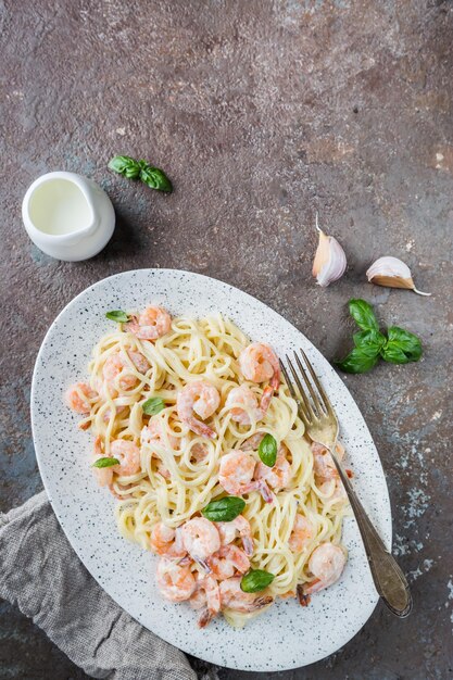 Espaguete de macarrão italiano em molho cremoso com camarão em um prato, vista de cima