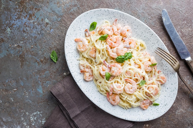 Espaguete de macarrão italiano em molho cremoso com camarão em um prato, vista de cima