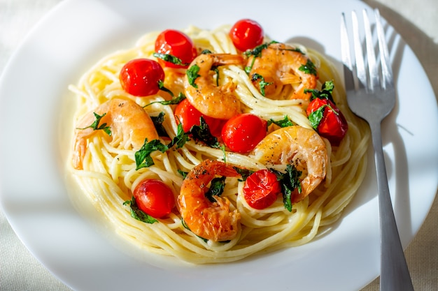 Foto espaguete de massa italiana com camarões e tomates. cozinha nacional.