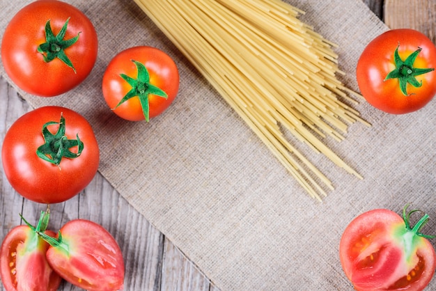 Espaguete e tomate em fundo de madeira