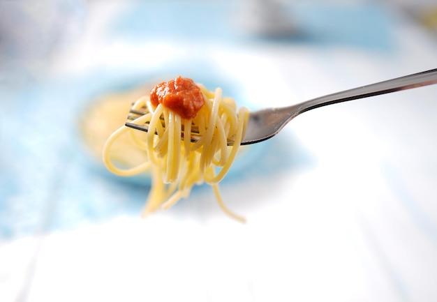 Espaguete em um garfo com molho de tomate.