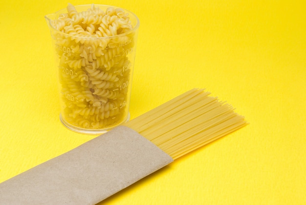 Foto espaguete em um saco de papel ecológico em um fundo amarelo copo de espaguete