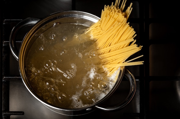 Espaguete fervendo na panela no fogão na cozinha.