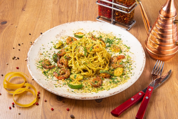 Espaguete Pesto com camarão e abobrinha servido na mesa de madeira vista lateral