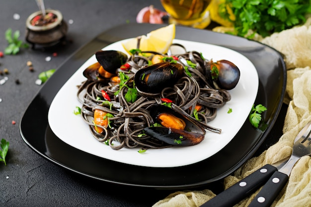 Espaguete preto. massa de frutos do mar preto com mexilhões sobre mesa preta. guloseimas mediterrânicas