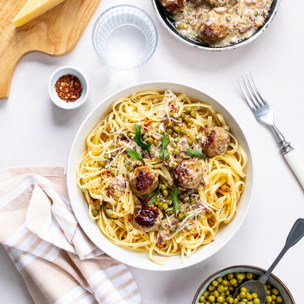 Foto el espagueti con albóndigas de carne y salsa de crema se sirve en un plato con hierbas y parmesán