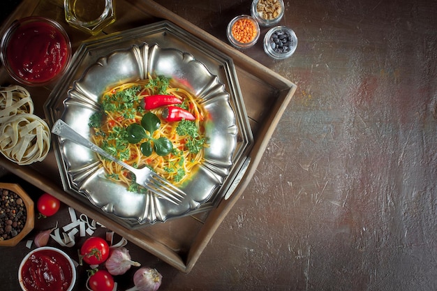 Foto espagueti hervido con condimentos y verduras sobre un fondo viejo