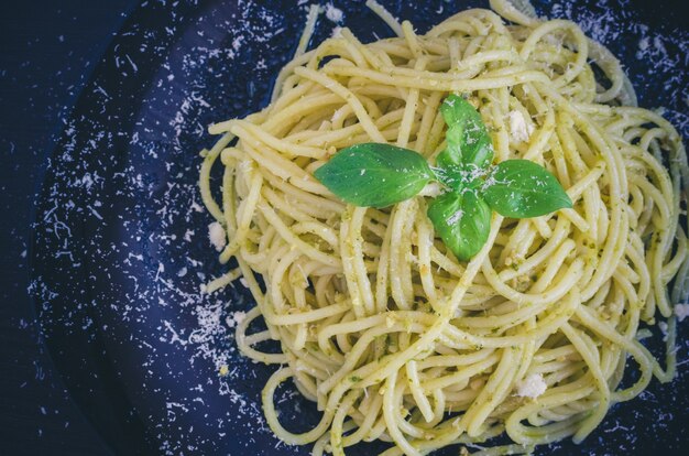 Espagueti de pasta italiana con salsa de pesto casero y hojas de albahaca