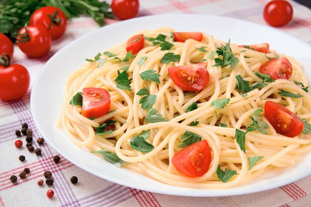 Espagueti de pasta con tomates cereza y perejil en un respaldo ligero