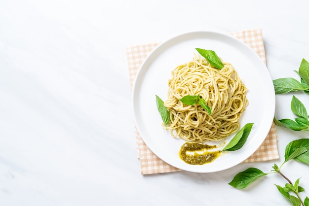 espagueti con salsa de pesto, aceite de oliva y hojas de albahaca.