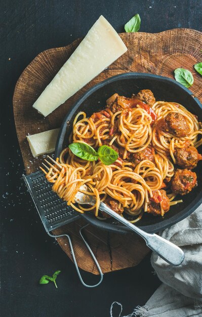 Espaguetis con albahaca albóndigas y queso parmesano en plato negro