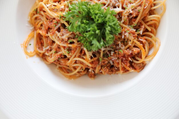 Espaguetis a la boloñesa con carne picada y salsa de tomate adornada con queso parmesano y albahaca, vista superior de comida italiana