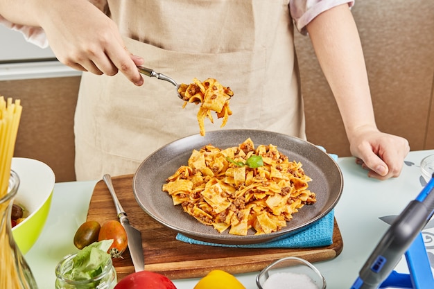 Espaguetis a la boloñesa cocidos del aprendizaje en línea usando la receta del panel táctil digital, prueba el plato terminado