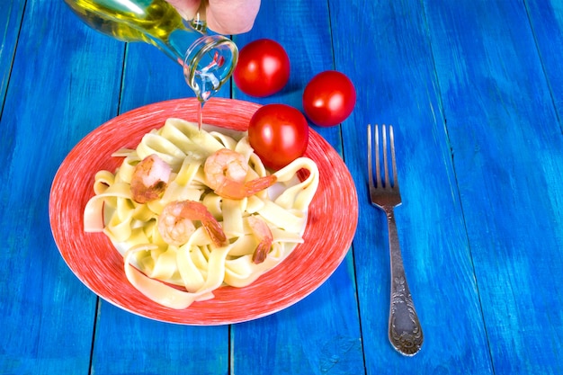 Espaguetis y camarones en plato blanco y tomates rojos.