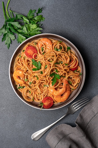 Espaguetis con camarones en salsa de crema de tomate sobre fondo negro