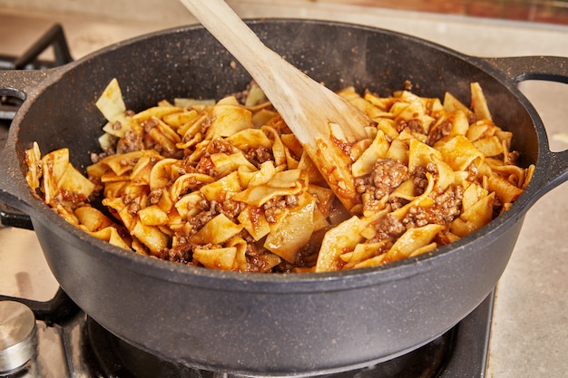 Espaguetis con carne molida y salsa, fritos en sartén para hacer espaguetis a la boloñesa según receta de Internet