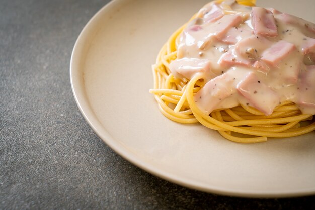 Foto espaguetis caseros con salsa de crema blanca con jamón - estilo italiano