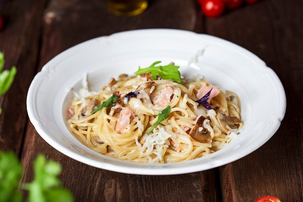 Espaguetis con champiñones y jamón en salsa de crema sobre una mesa de madera