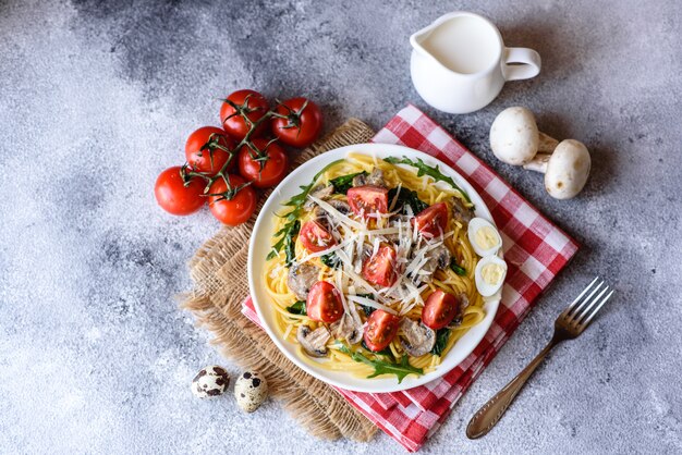 Espaguetis con champiñones, queso, espinacas, rukkola y tomates cherry. Plato italiano, cultura mediterránea