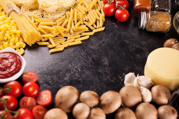 Espaguetis crudos italianos y pasta cruda sobre fondo vintage de madera oscura.