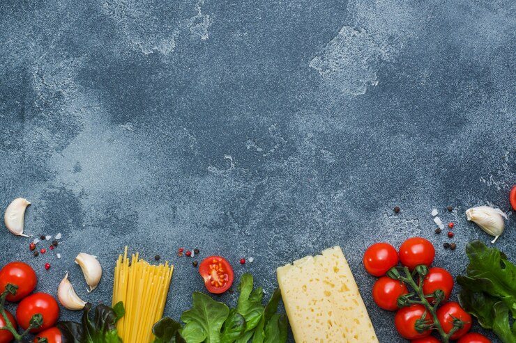 Espaguetis crudos de pasta italiana e ingredientes de cocina Tomates cherry Verduras de queso. Comida italiana superficie de piedra oscura. Vista superior con espacio de copia.