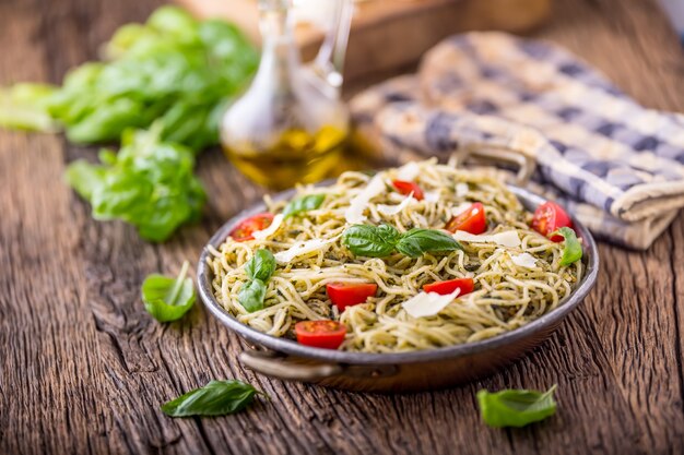 Espaguetis. Espaguetis de pasta italiana con pesto de albahaca, tomates cherry y aceite de oliva.