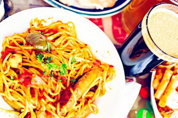 Espaguetis frescos con salchichas, pimientos y cebollas en un restaurante italiano.