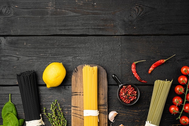 Espaguetis multicolores con ingredientes, sobre fondo de mesa de madera negra, vista superior plana, con espacio para copiar texto