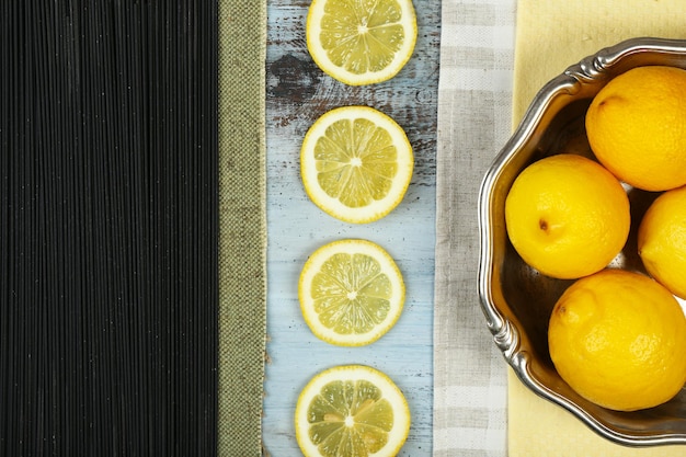 Espaguetis negros y limones en la vista superior de la mesa de madera