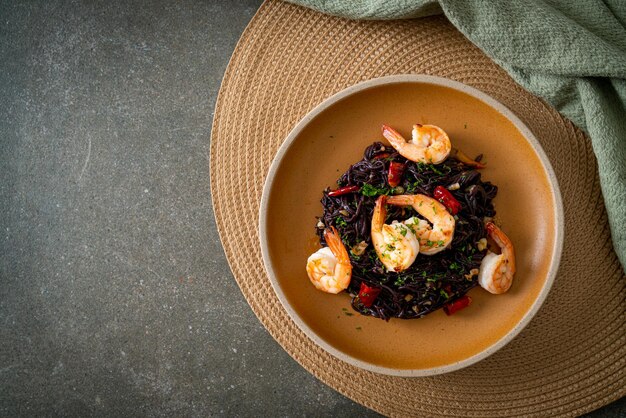 espaguetis negros salteados con ajo y gambas en un plato