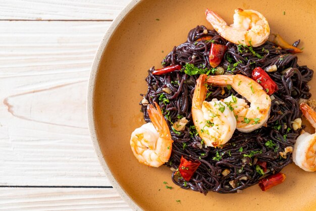 espaguetis negros salteados con ajo y gambas en un plato