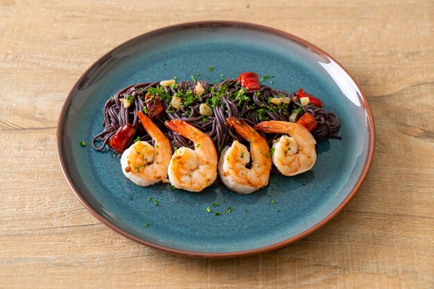 espaguetis negros salteados con ajo y gambas en un plato