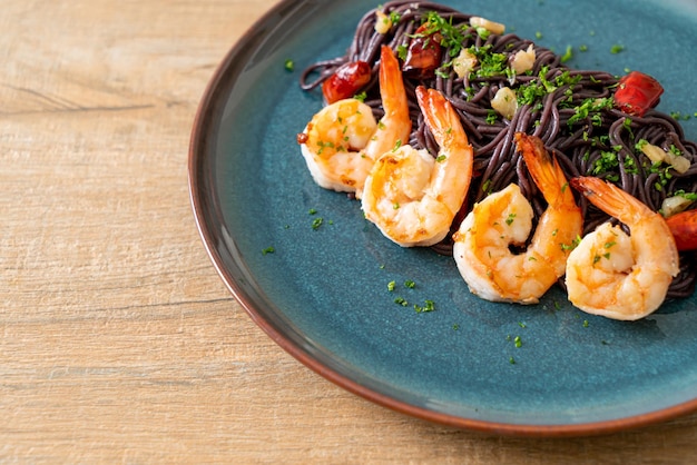 espaguetis negros salteados con ajo y gambas en un plato