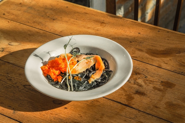 Espaguetis negros sofritos con los salmones en la tabla.