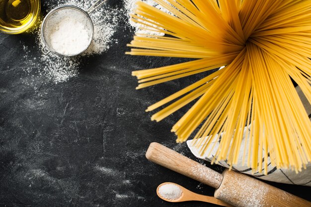 Espaguetis de pasta casera haciendo fondo sobre textura negra, espacio de copia, vista superior