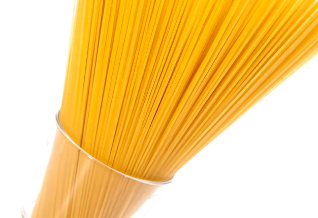 Espaguetis de pasta cruda sobre fondo blanco.